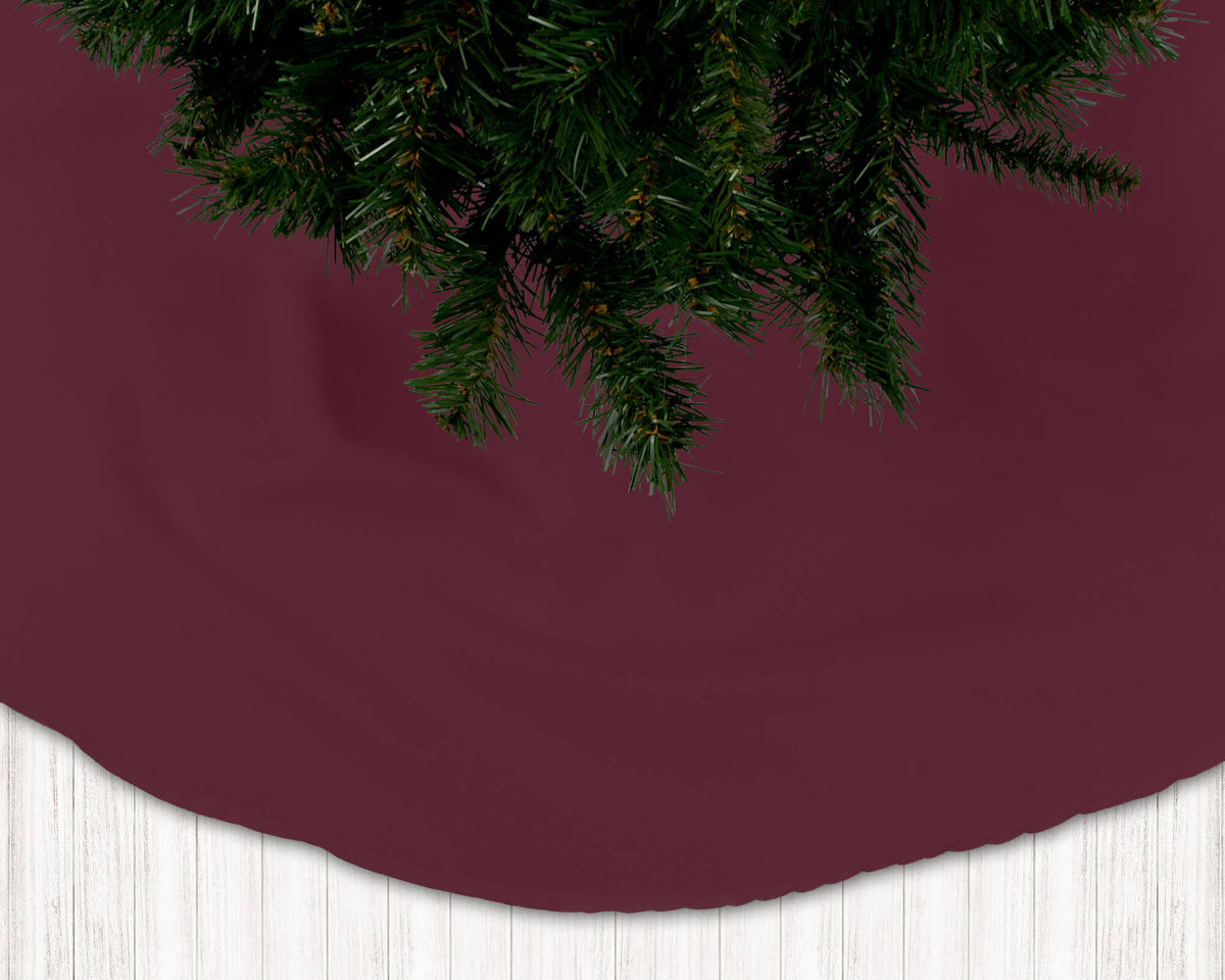 Burgundy Christmas tree skirt with a tree on a white floor.