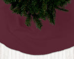 Burgundy Christmas tree skirt with a tree on a white floor.