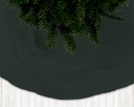 Dark green Christmas tree skirt with pine tree branches on a dark background