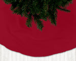 Red Christmas tree skirt with a portion of a decorated tree visible.