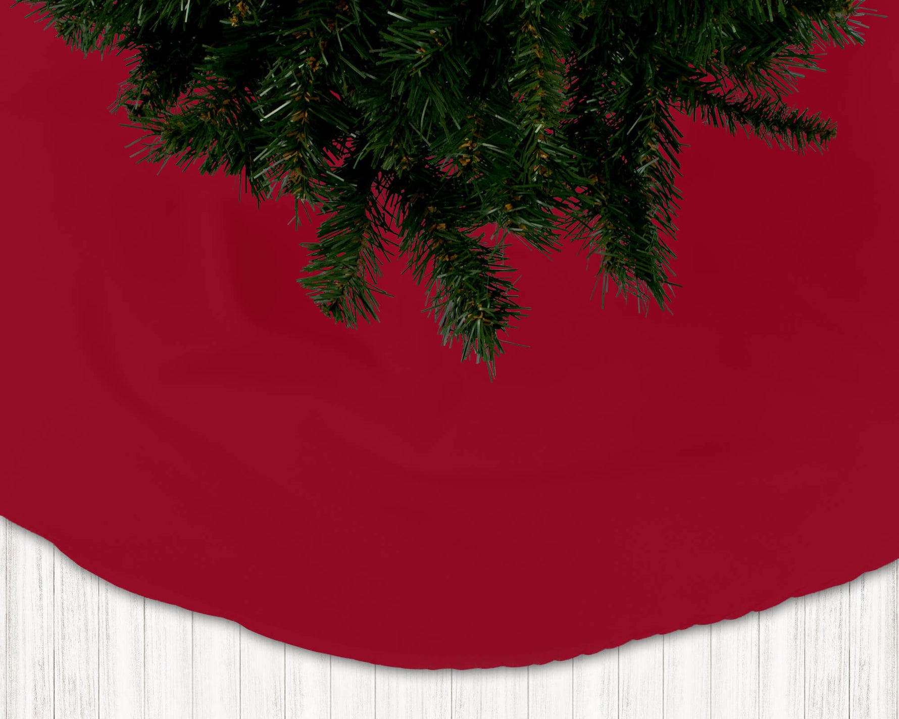 Red Christmas tree skirt with a portion of a decorated tree visible.