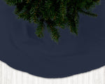 Navy blue Christmas tree skirt with pine tree branches on a dark background