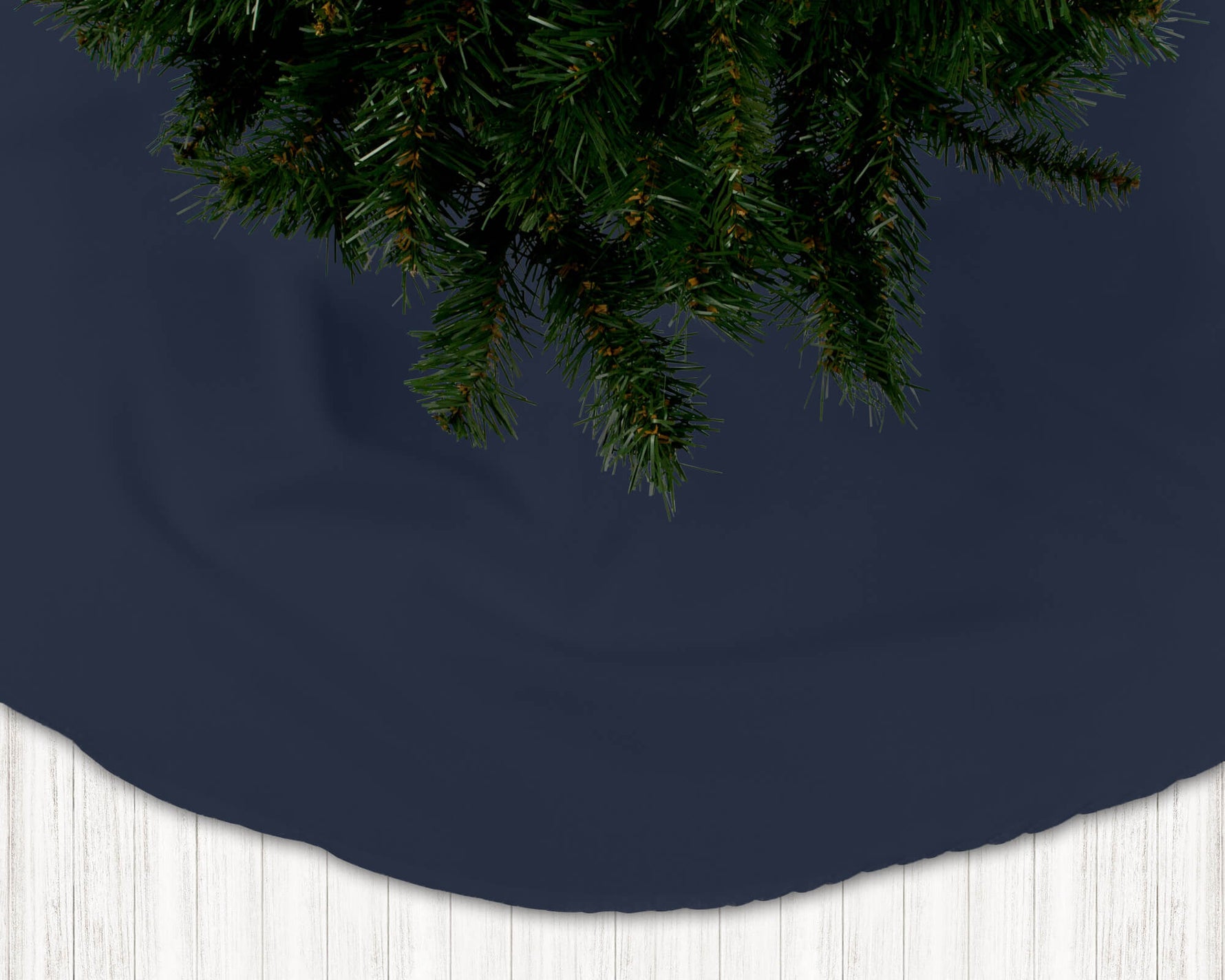 Navy blue Christmas tree skirt with pine tree branches on a dark background