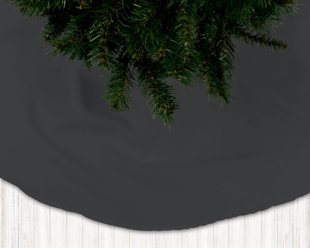 Dark gray Christmas tree skirt with a section of a decorated tree on a white floor.