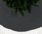 Dark gray Christmas tree skirt with a section of a decorated tree on a white floor.