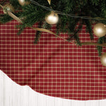 Red plaid Christmas tree skirt with greenery and gold ribbon