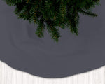 Dark gray Christmas tree skirt with green pine branches on a dark background