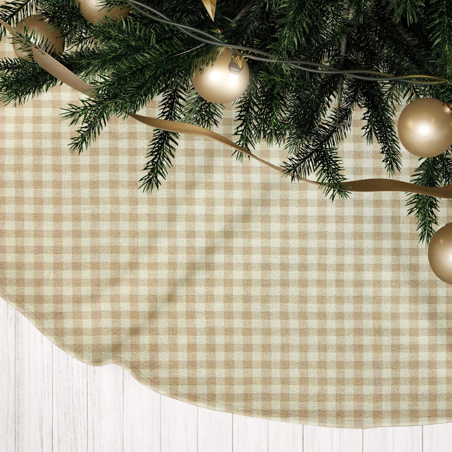 Christmas tree skirt with greenery, gold ribbons, and ornaments on a checkered fabric background.