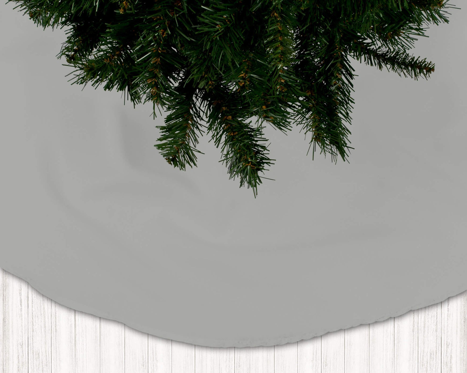 Gray Christmas tree skirt with green pine tree branches on a light gray background