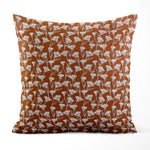 Decorative pillow with white floral pattern on a rust-colored background